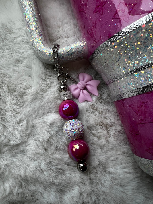 Decorative charm with beads and sparkles on a tumbler set on a fluffy surface