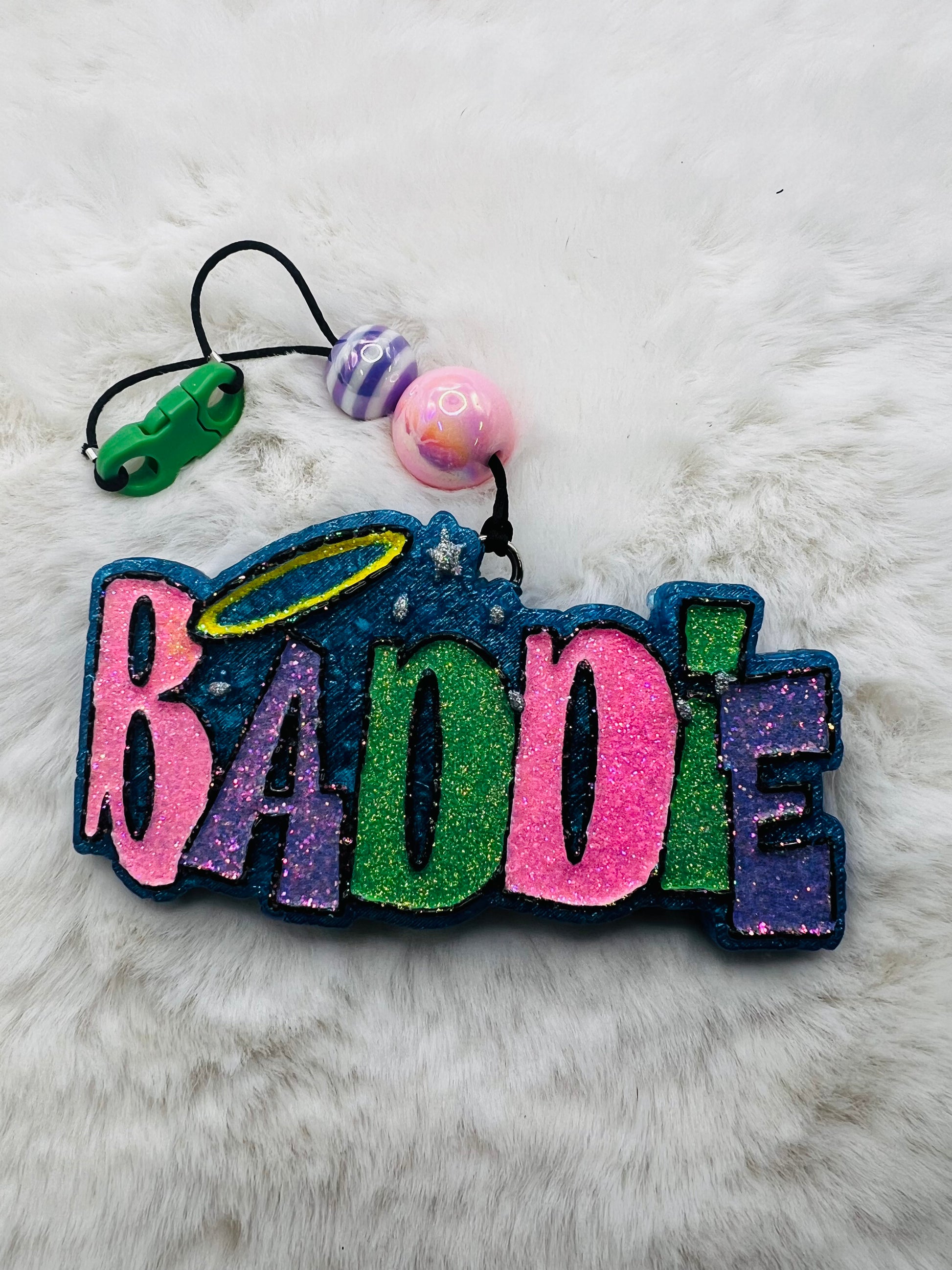 Colorful freshie with 'BADDIE' text on a fluffy white surface