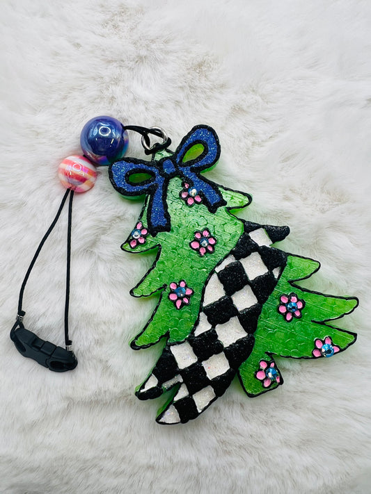 Decorative freshie with green tree design, blue bow, and colorful beads on a white fluffy background