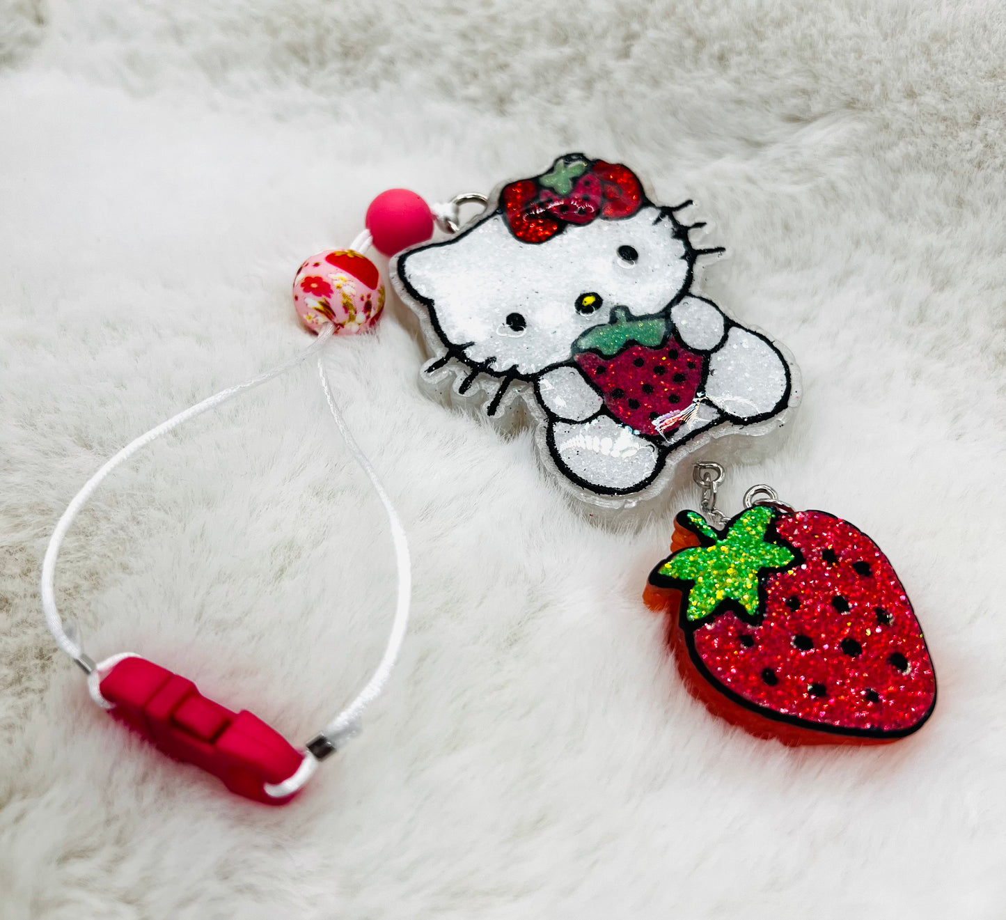 Hello Kitty charm with strawberry on a fluffy white surface