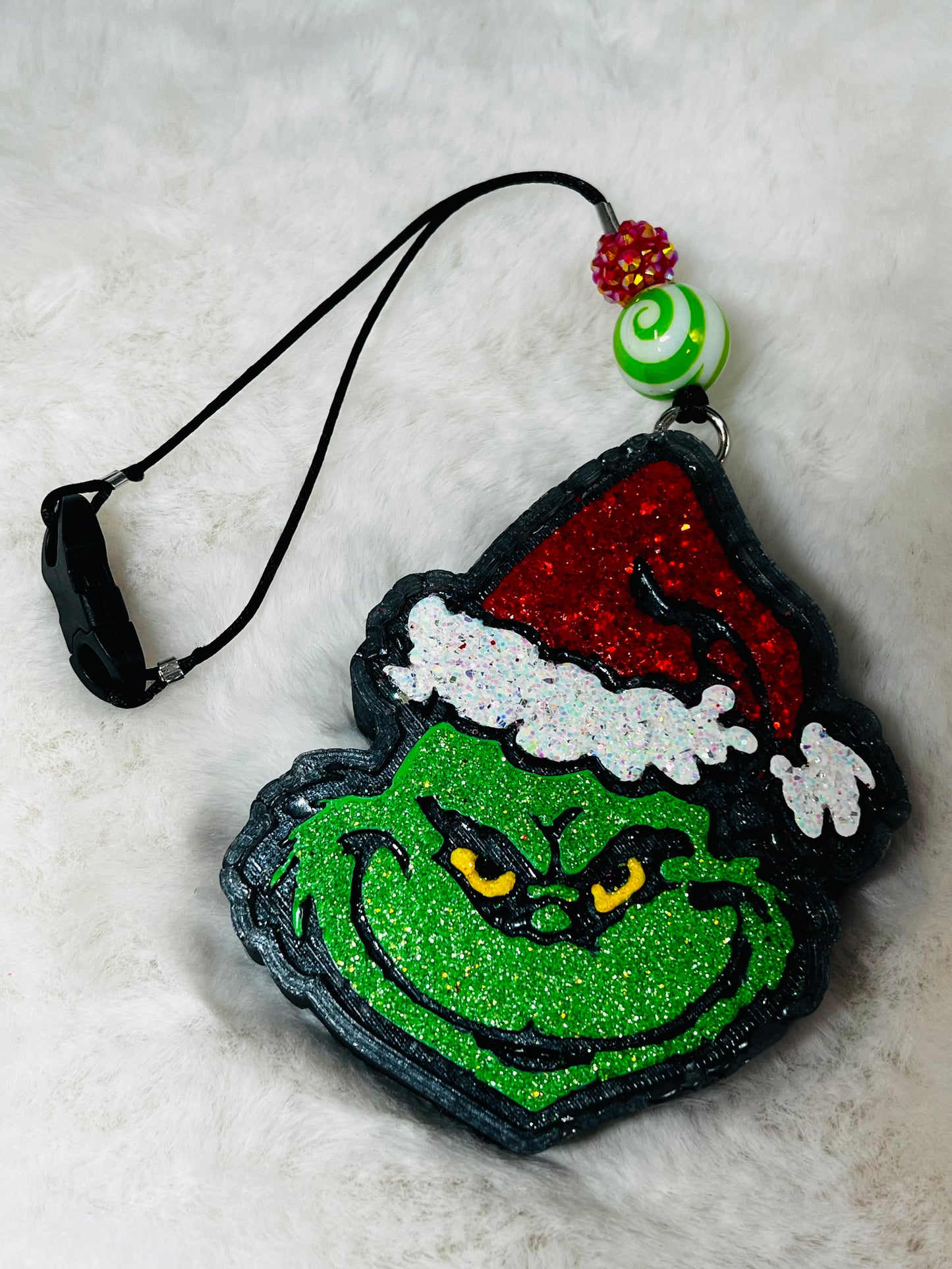 Decorative freshie with Grinch face design on a textured surface