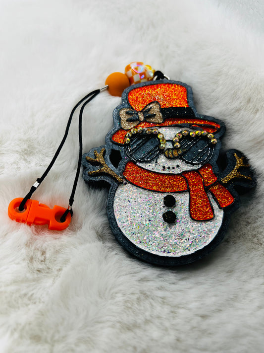 Decorative snowman freshie with orange hat and scarf on a fluffy white background