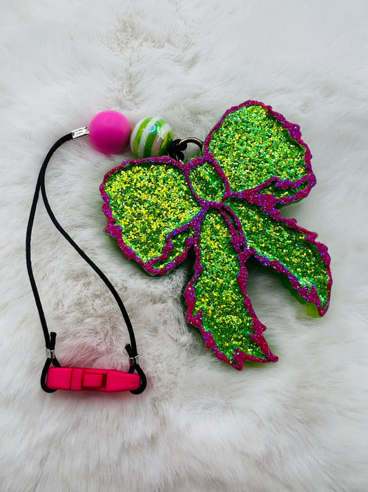 Green glittery bow freshie with pink accents on a white fur background