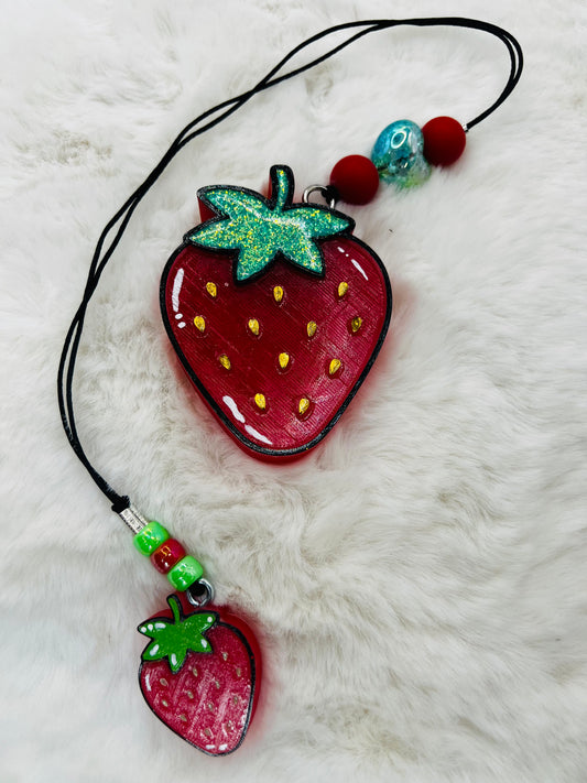 Strawberry-shaped charms on a two-piece bookmark on a white fur background