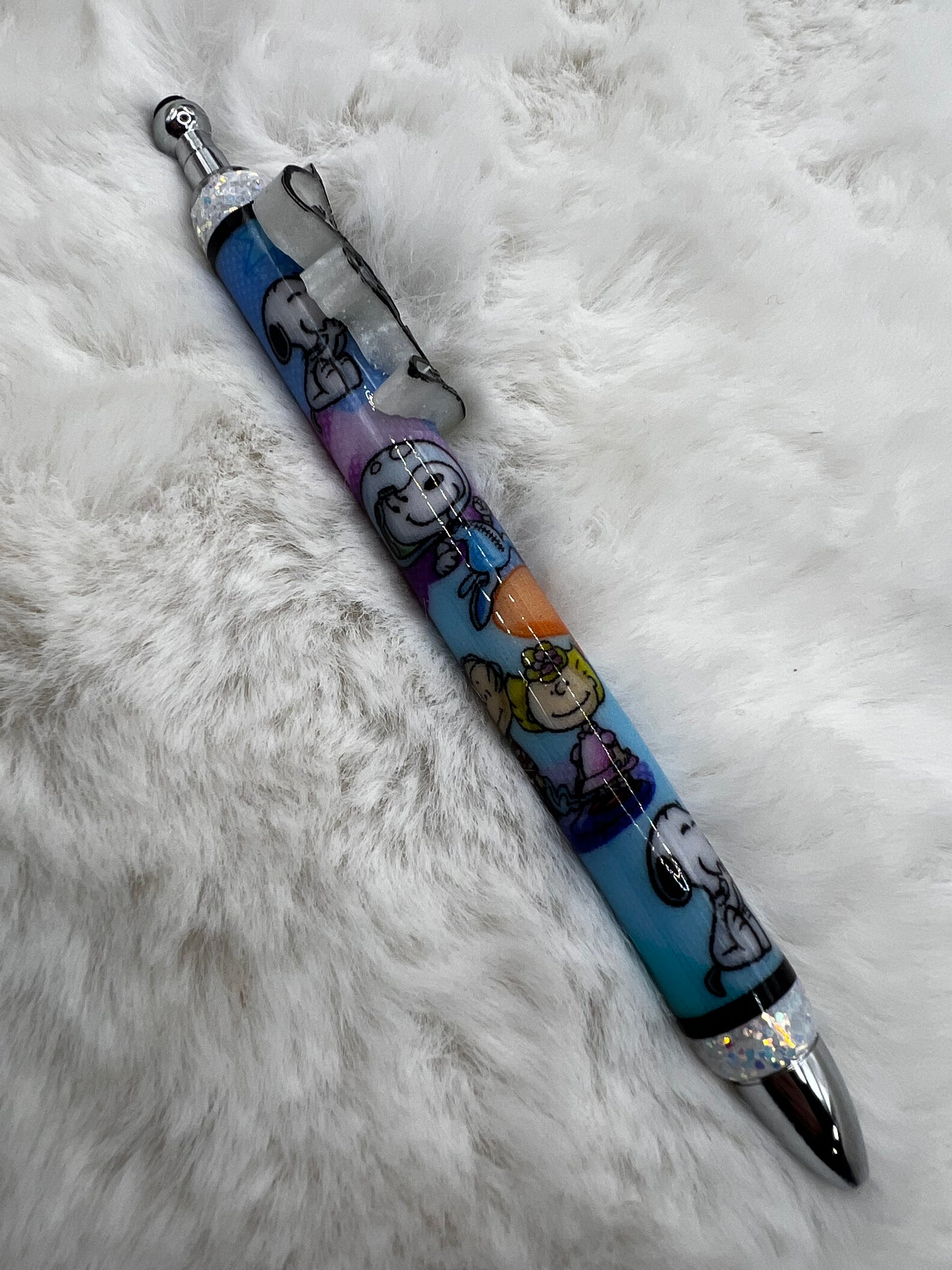 Pen with Peanuts cartoon character designs on a fluffy white surface
