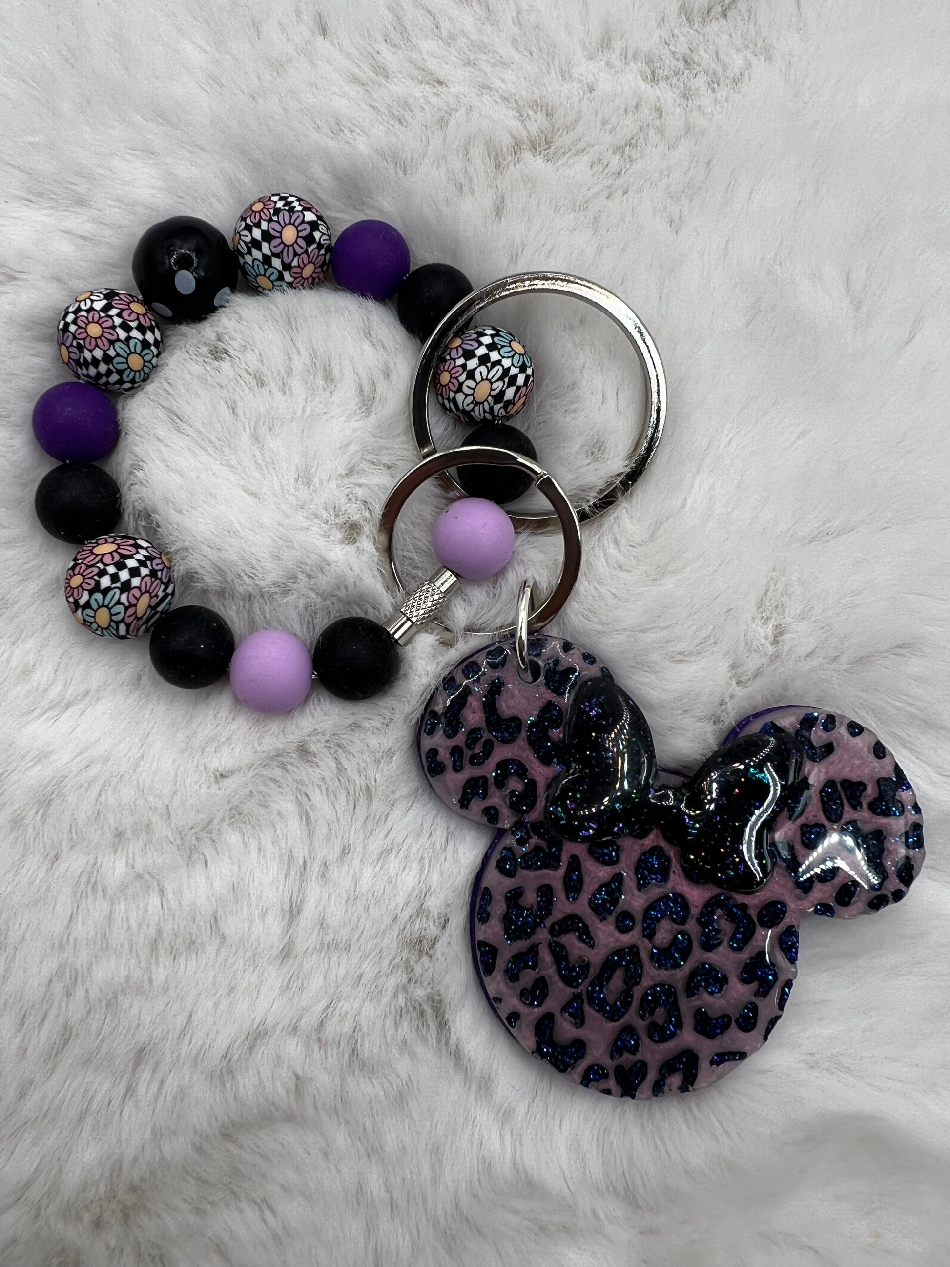 Bracelet with purple and black beads and a keychain with a leopard print Minnie Mouse design on a white fur background