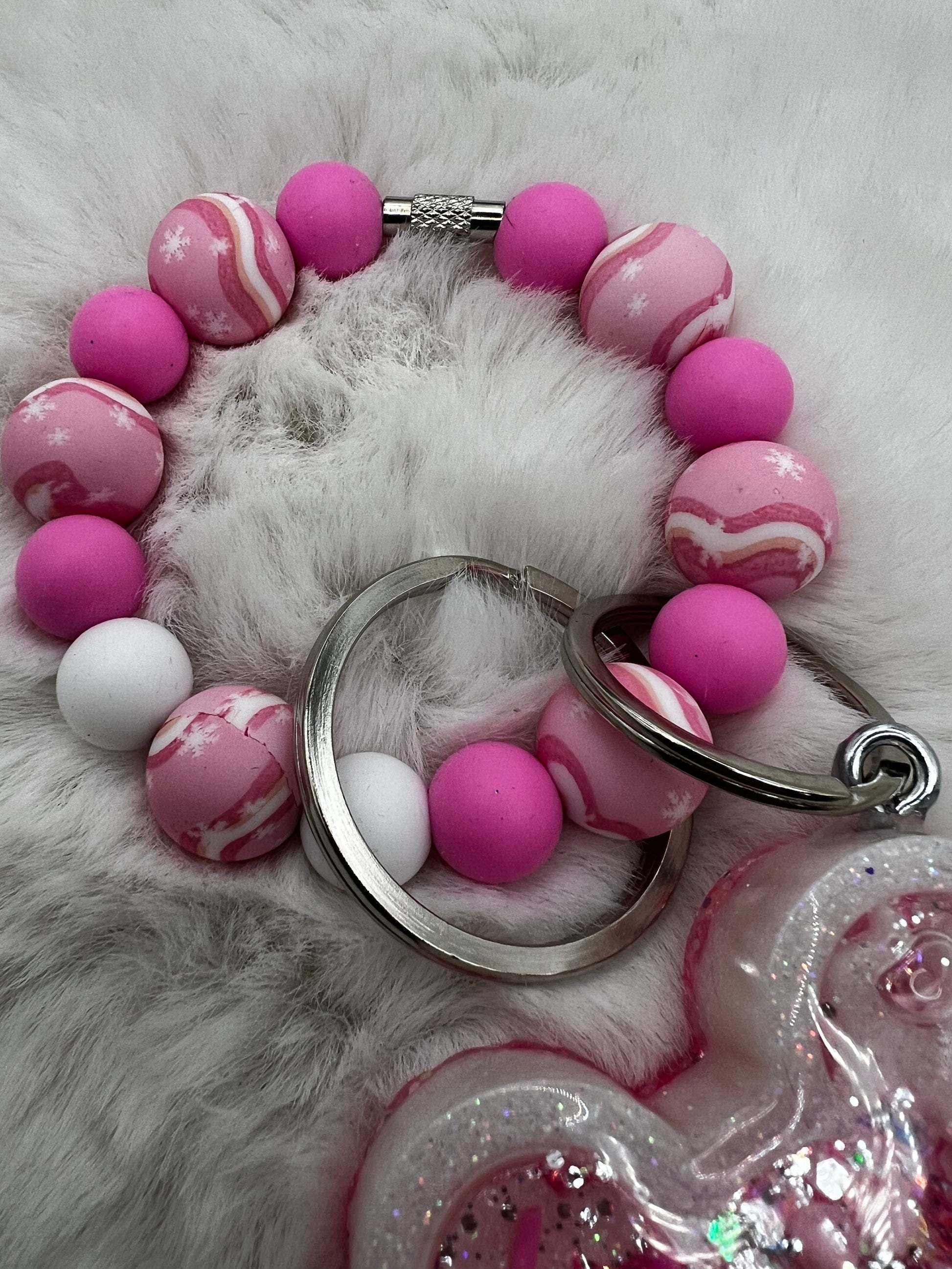 Pink and white marbled beads on a keychain on a fluffy white surface
