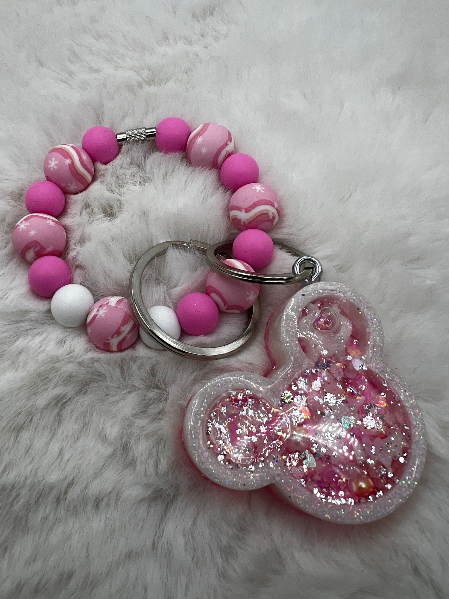 Pink and white beaded keychain with a glittery Minnie Mouse charm on a fluffy white background