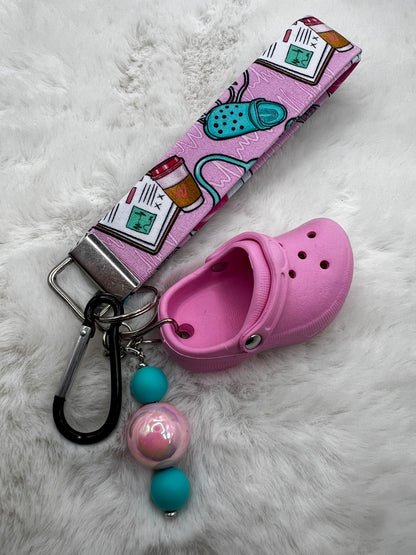 Pink croc shoe lanyard keychain with colorful beads and a lanyard on a white fur background