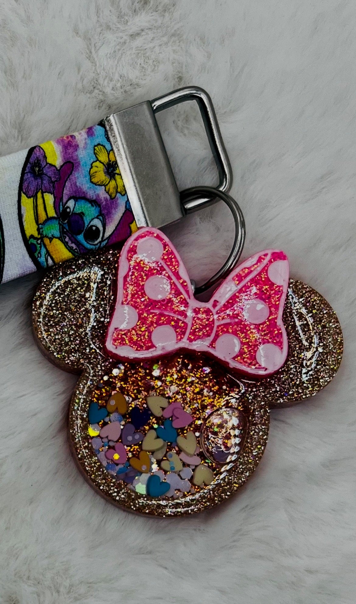 Colorful lanyard keychain featuring Minnie Mouse with a bow and glittery design on a marble surface