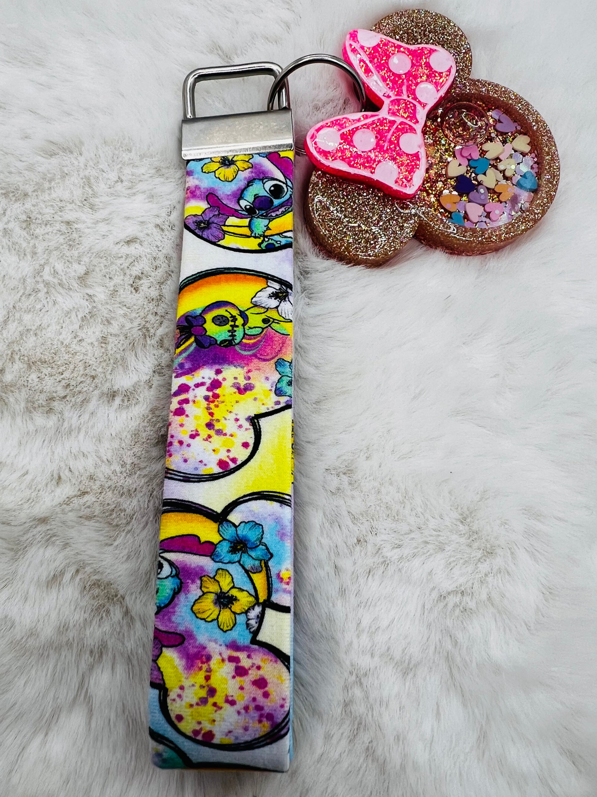 Colorful keychain strap with featuring Minnie Mouse and Stitch designs on a fluffy white surface