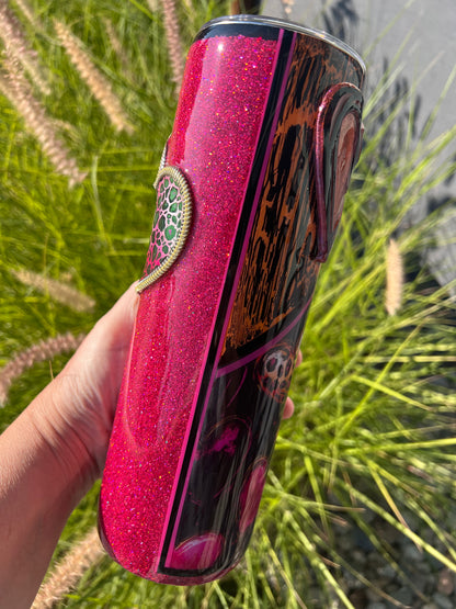 Pink glittery tumbler with a design held in front of grass