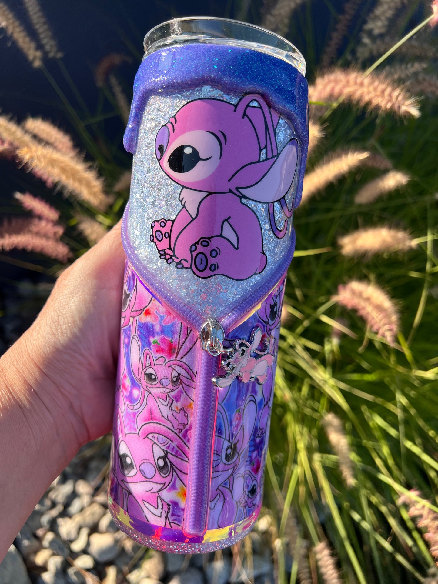 Hand holding a purple glittery tumbler with cartoon character Angel of Lilo & Stitch design against a natural background