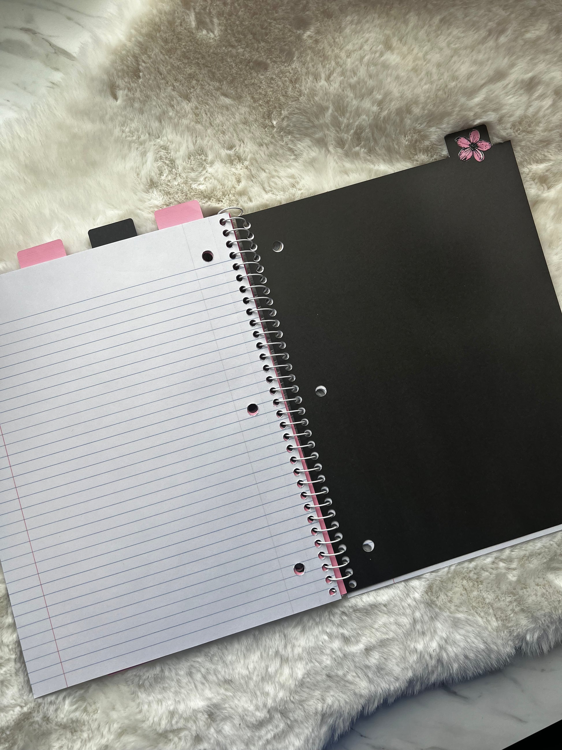 Notebook with a black cover and lined pages on a textured surface
