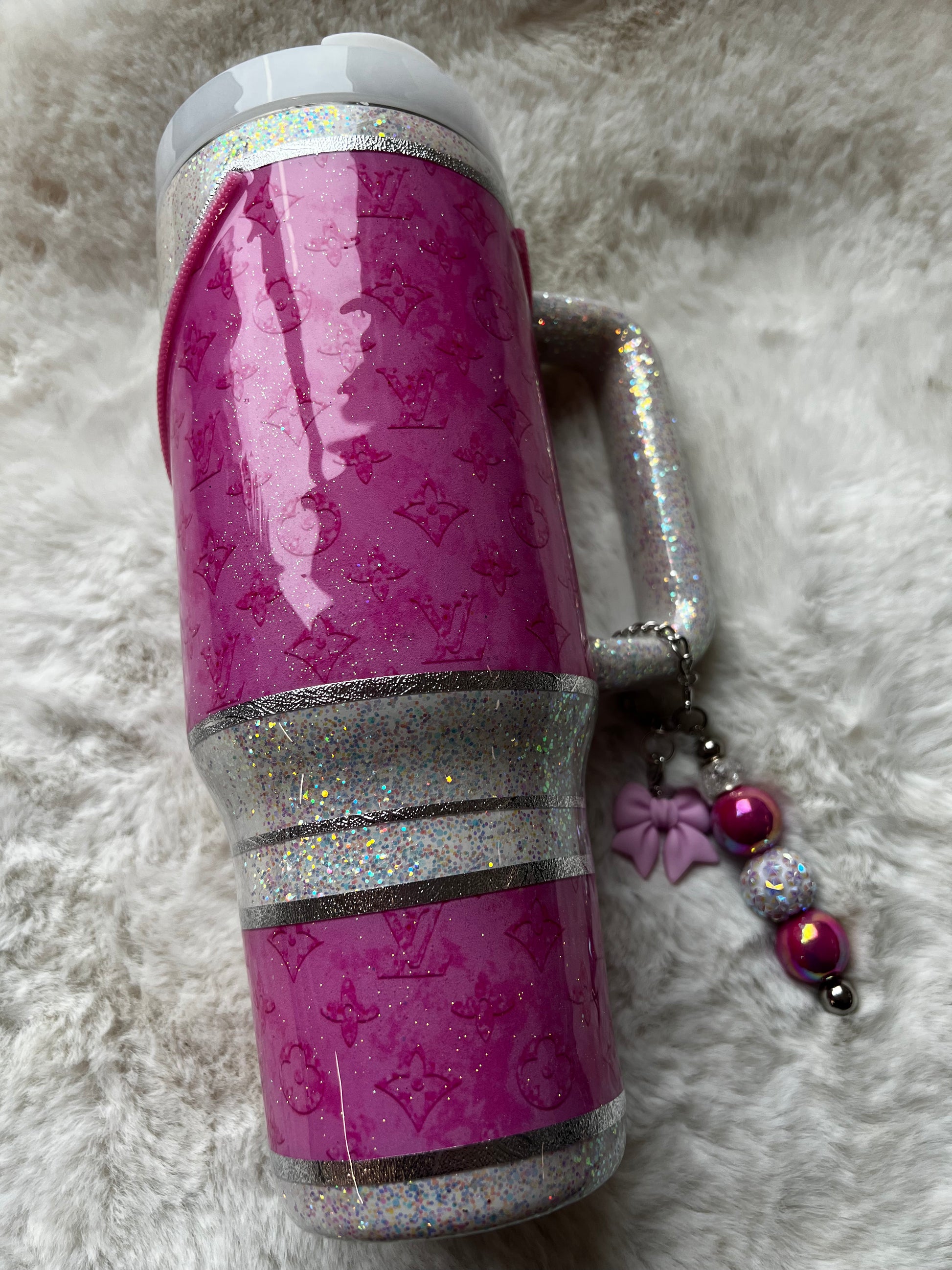 Pink glittery tumbler with handle on a fluffy white surface