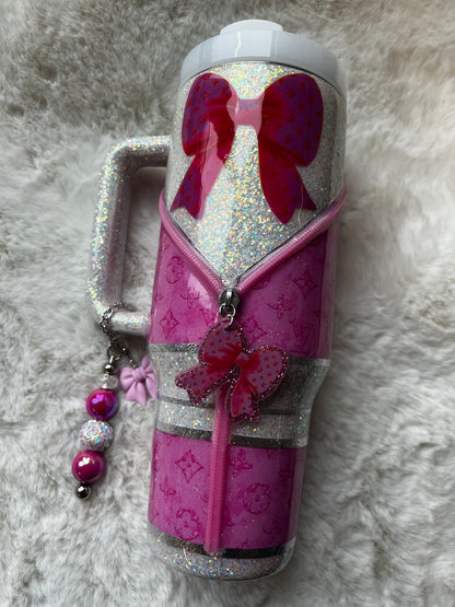 Decorative pink and silver tumbler with bow design on a textured gray background