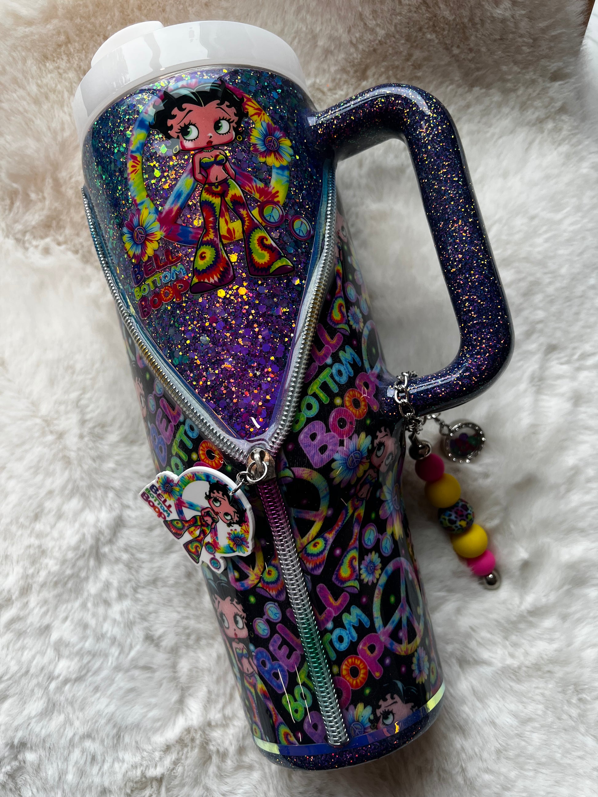 Colorful glittery tumbler with Betty Boop character design on a white fluffy surface