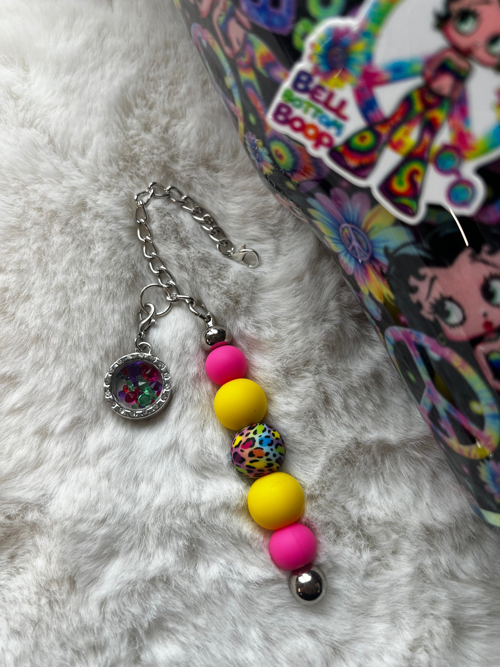 Colorful glittery tumbler with Betty Boop character design and beads on a white fluffy surface