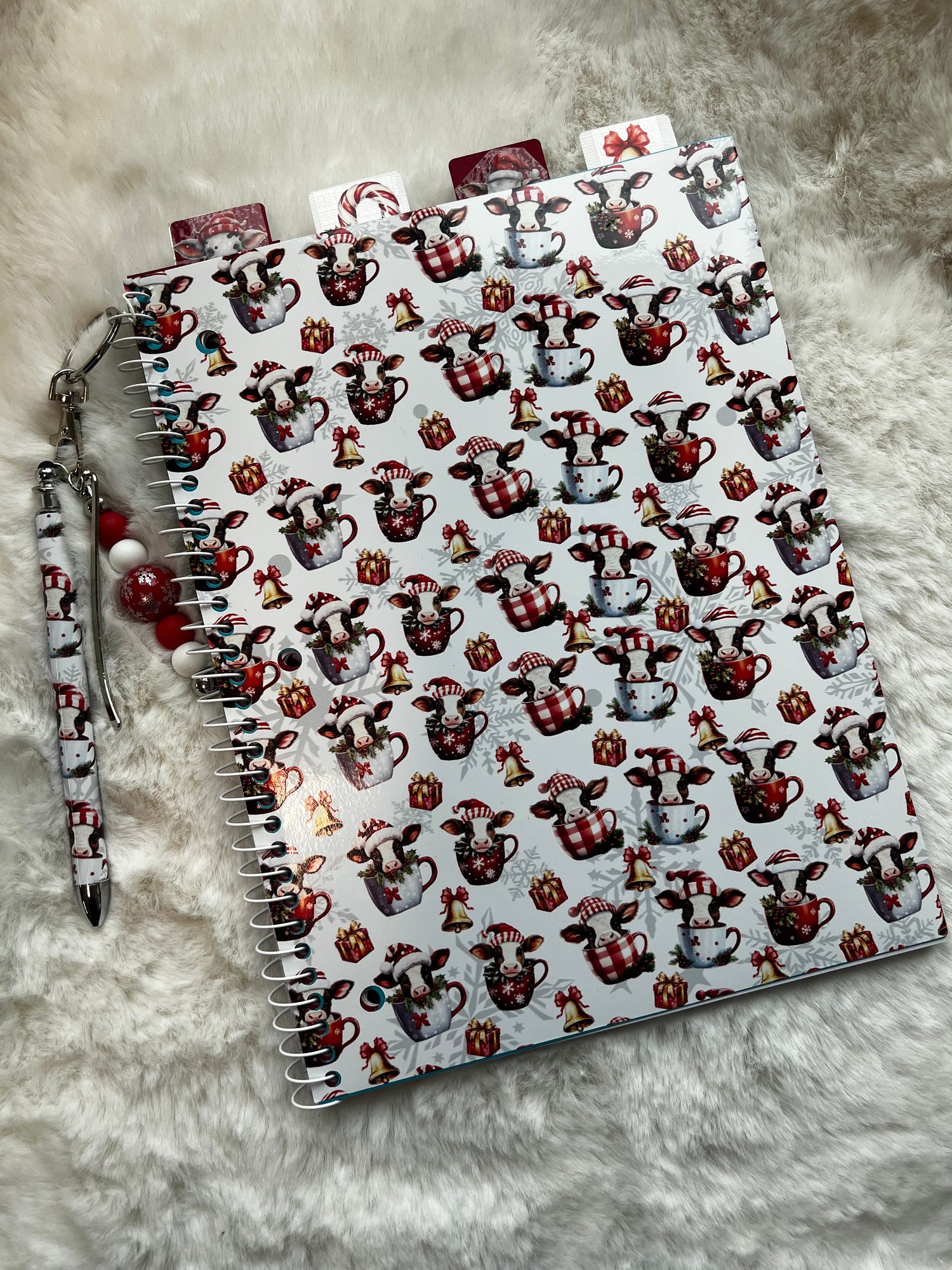 Notebook with cow pattern on cover and pen on gray surface