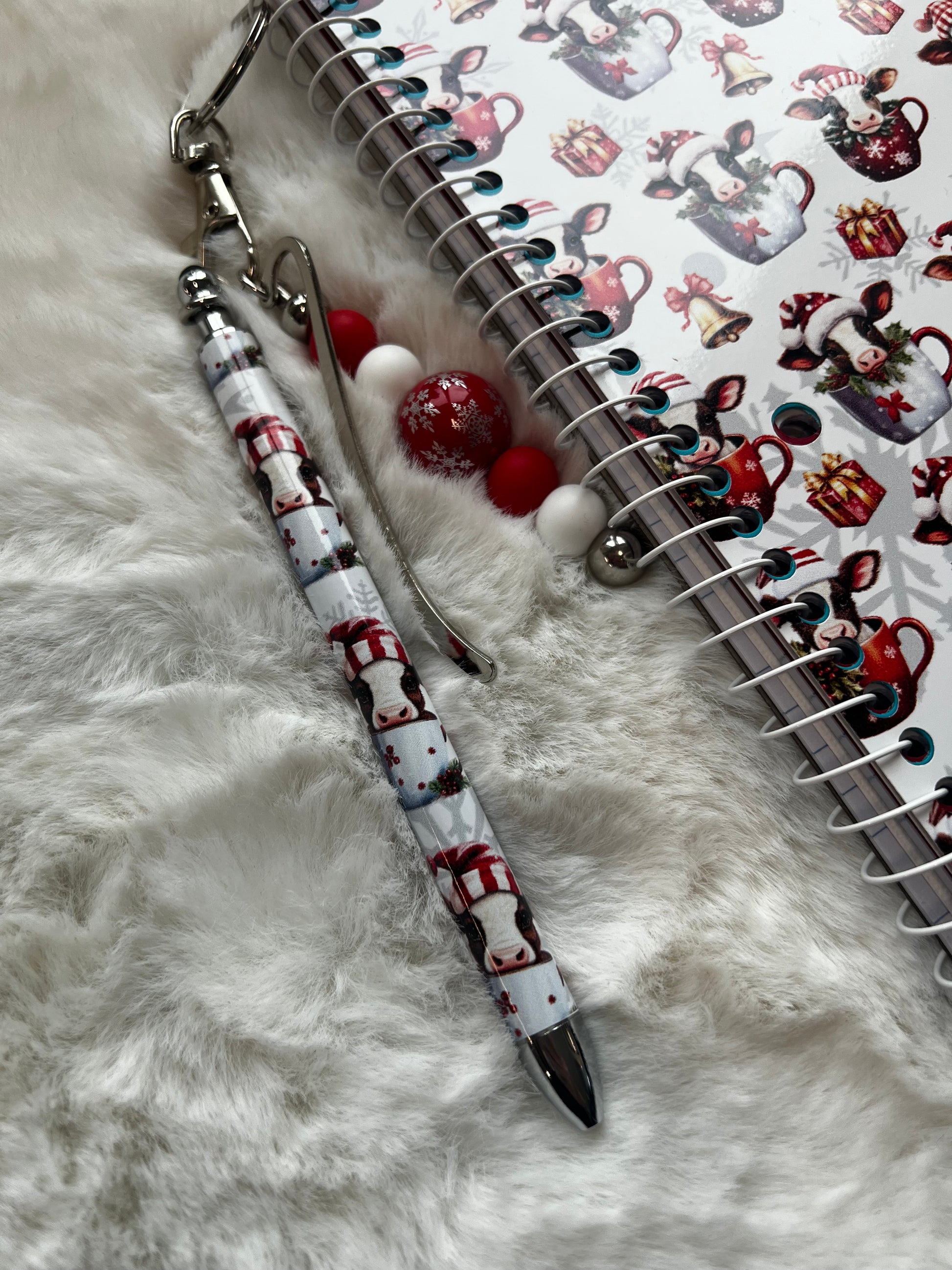 Decorative pen with cow design on a notebook with Christmas-themed stickers.