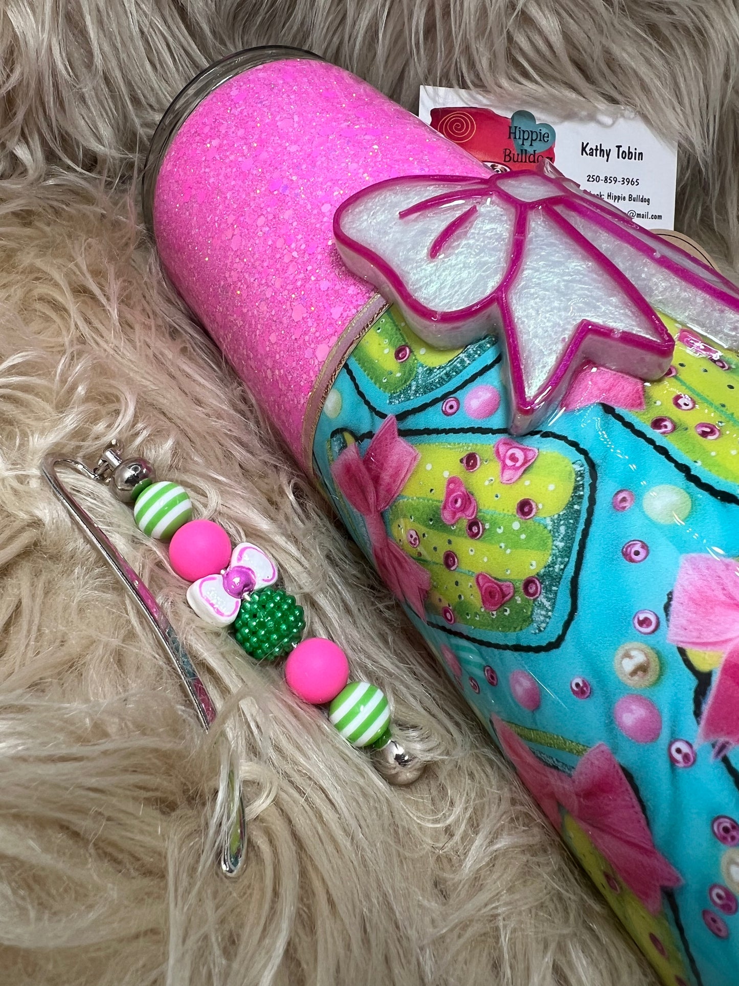 Decorative tumbler with colorful design and charm on a fluffy surface