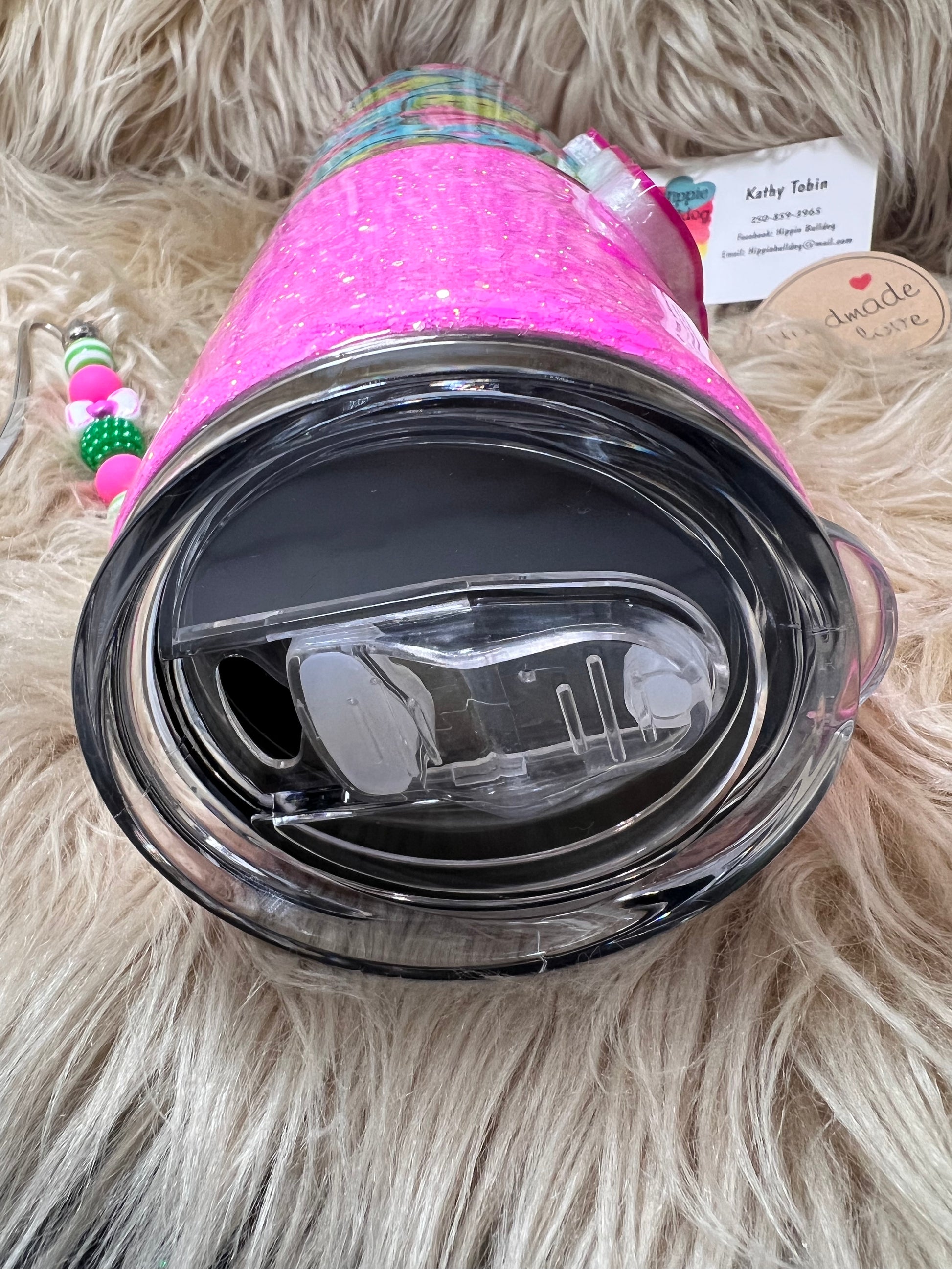 Clear tumbler with pink glittery lid on a fluffy white surface