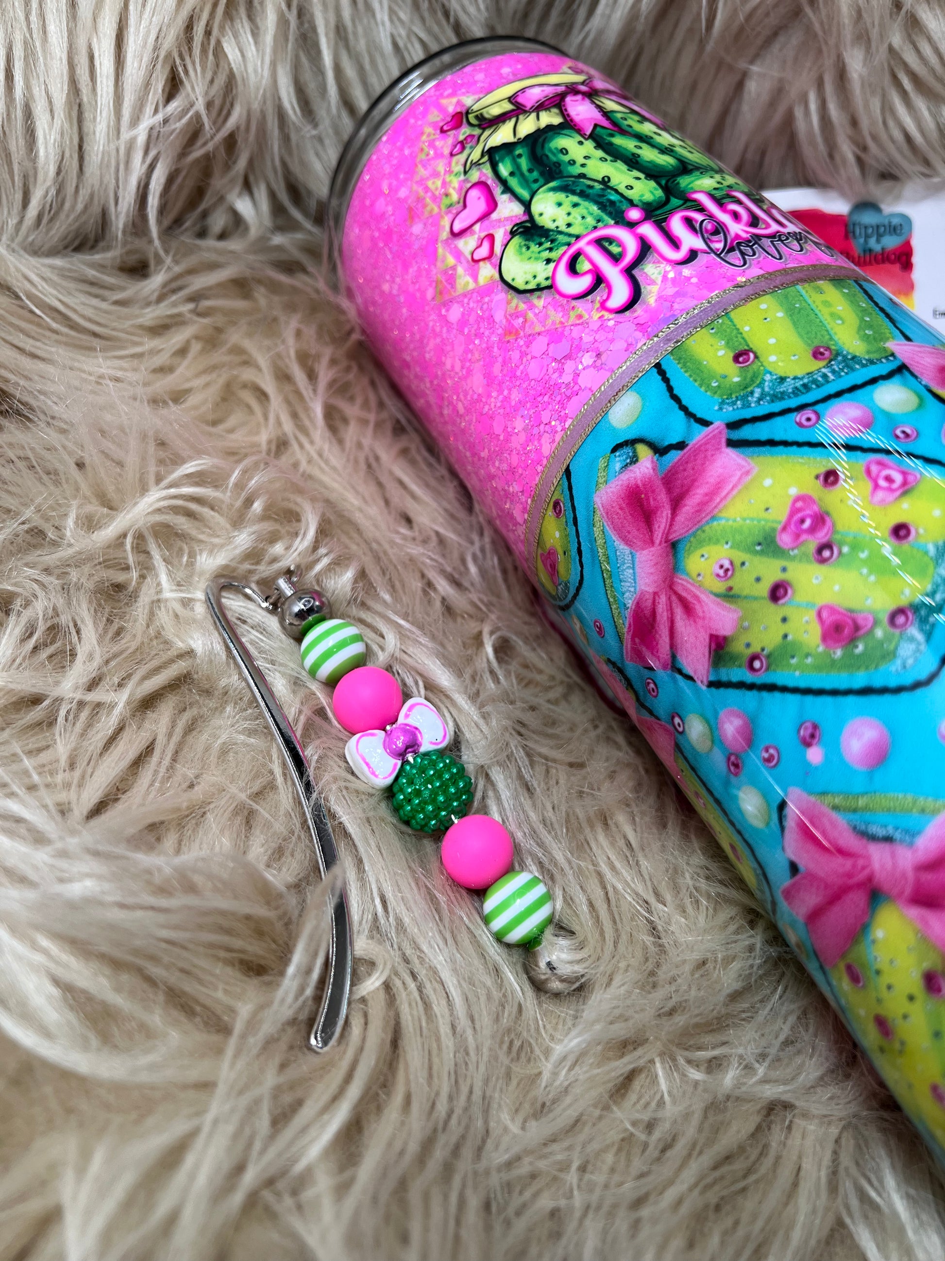 Colorful tumbler with decorative charm on a fluffy surface